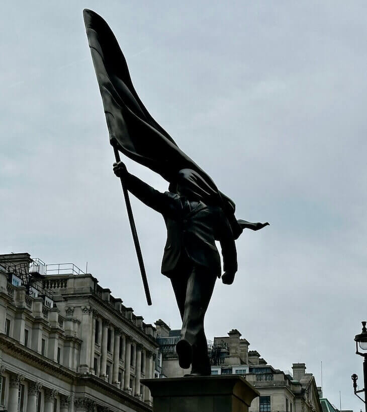 Banksy statue with the suited figure holding a huge flag